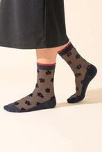 Load image into Gallery viewer, A pair of delicate black sheer socks with pretty black daisy design with red centre and red trim at ankle! Lightweight and breathable, they offer a comfortable, weightless fit for all-day elegance.