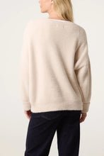 Load image into Gallery viewer, A woman shown from the back wearing a fuzzy, oversized cream-colored knit sweater and dark navy pants, photographed against a clean white studio background.